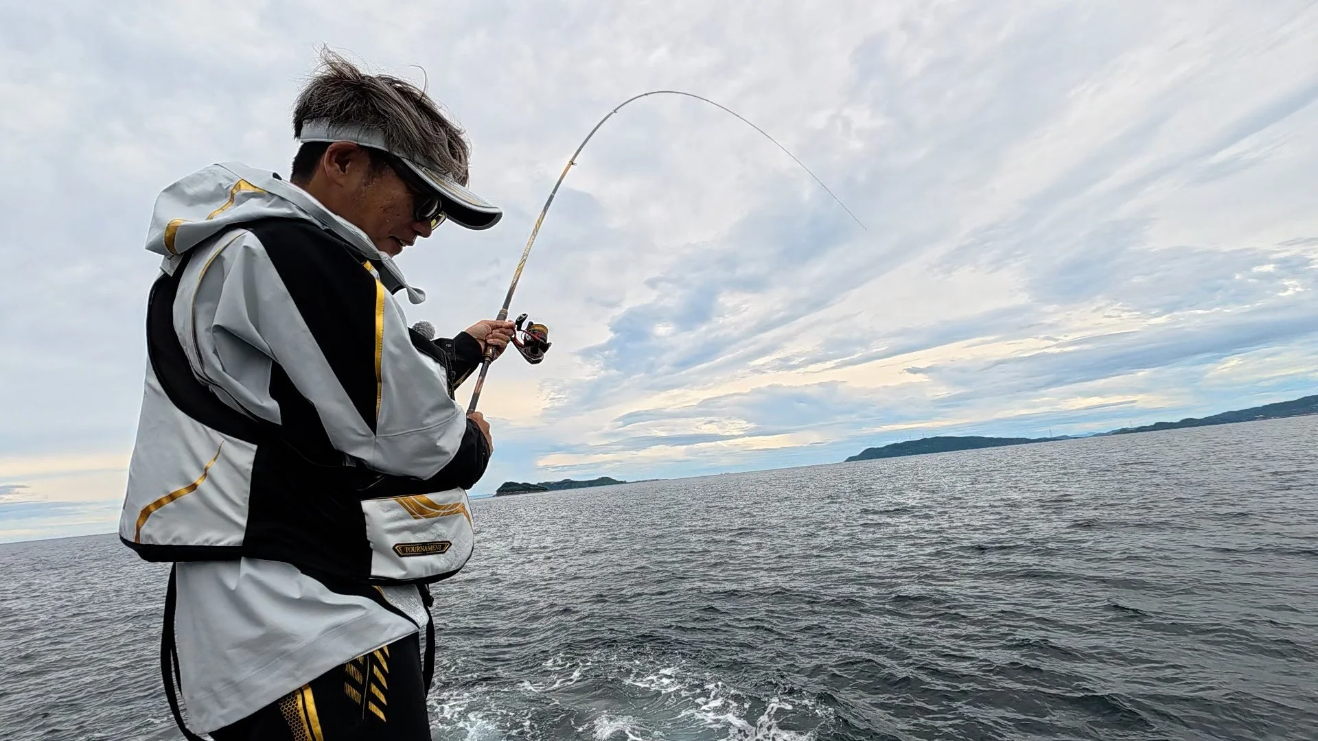 釣り竿がしなり、魚がかかっている様子の男性