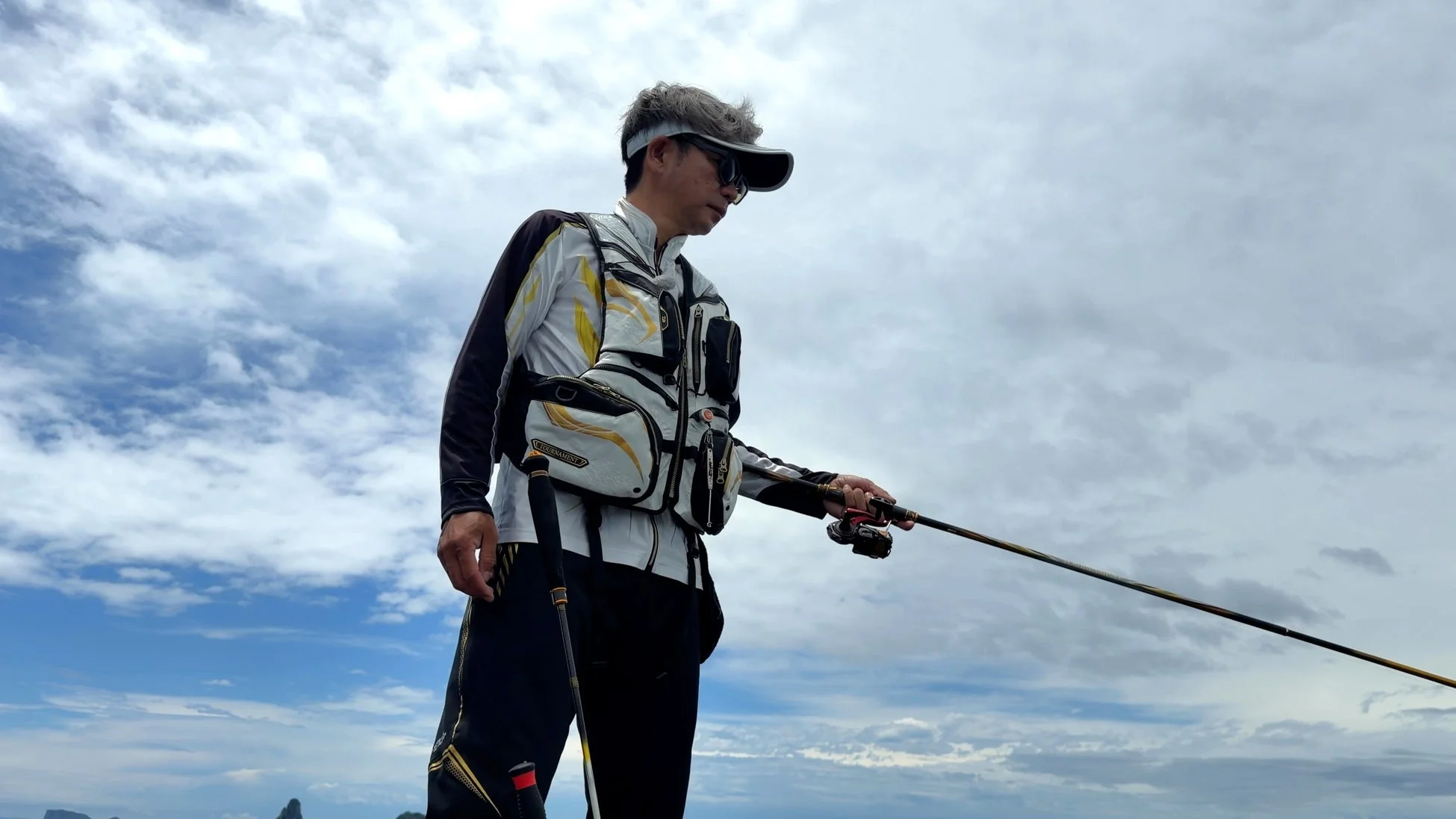 釣りウェアを着用し、海辺で釣りに挑む田中貴氏