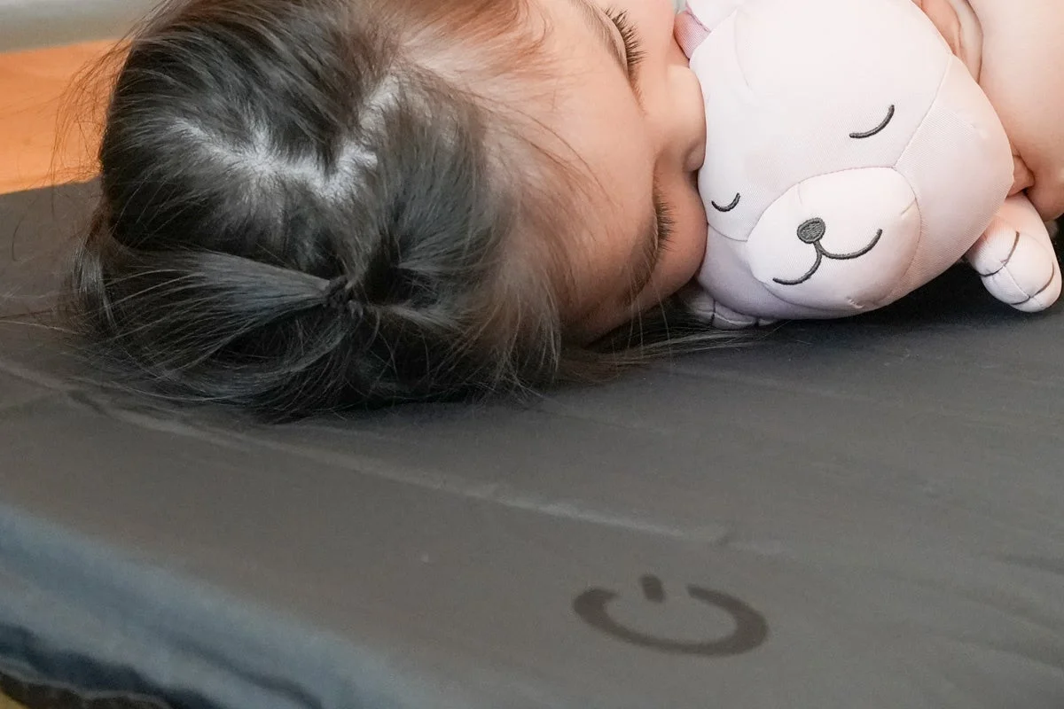 ピンクのぬいぐるみを抱きしめて横向きに安らかに眠る子供のクローズアップ画像