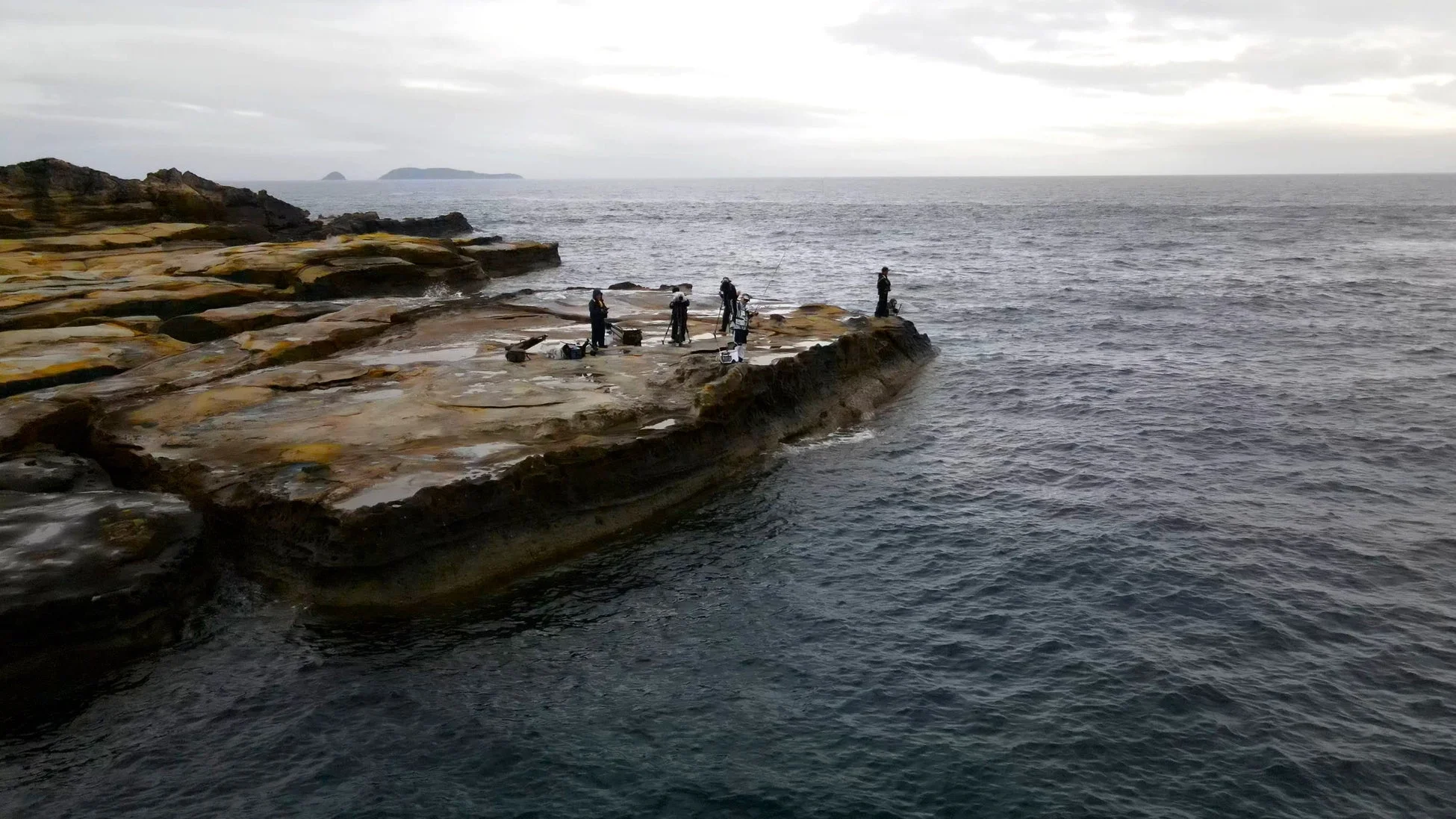 岩場の海岸線で磯釣りを楽しむ人々