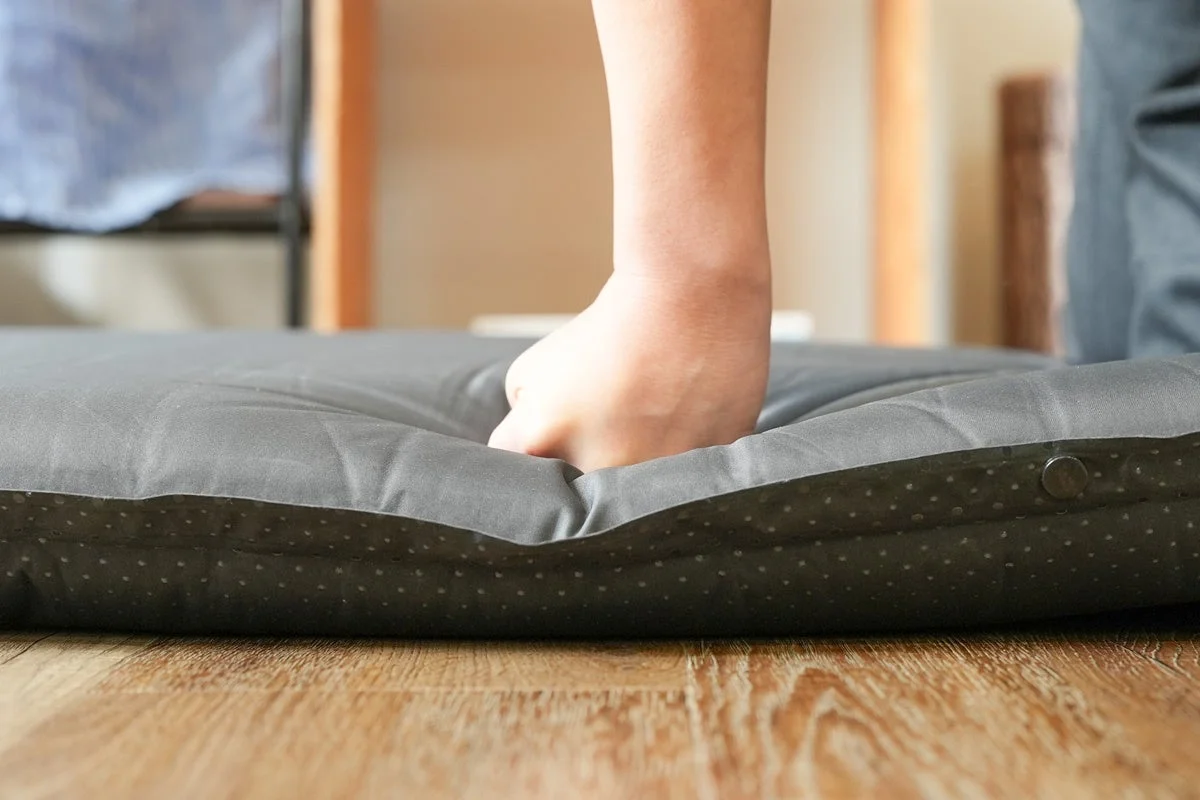 裸足で柔らかい灰色のマットレスを踏みつけている様子