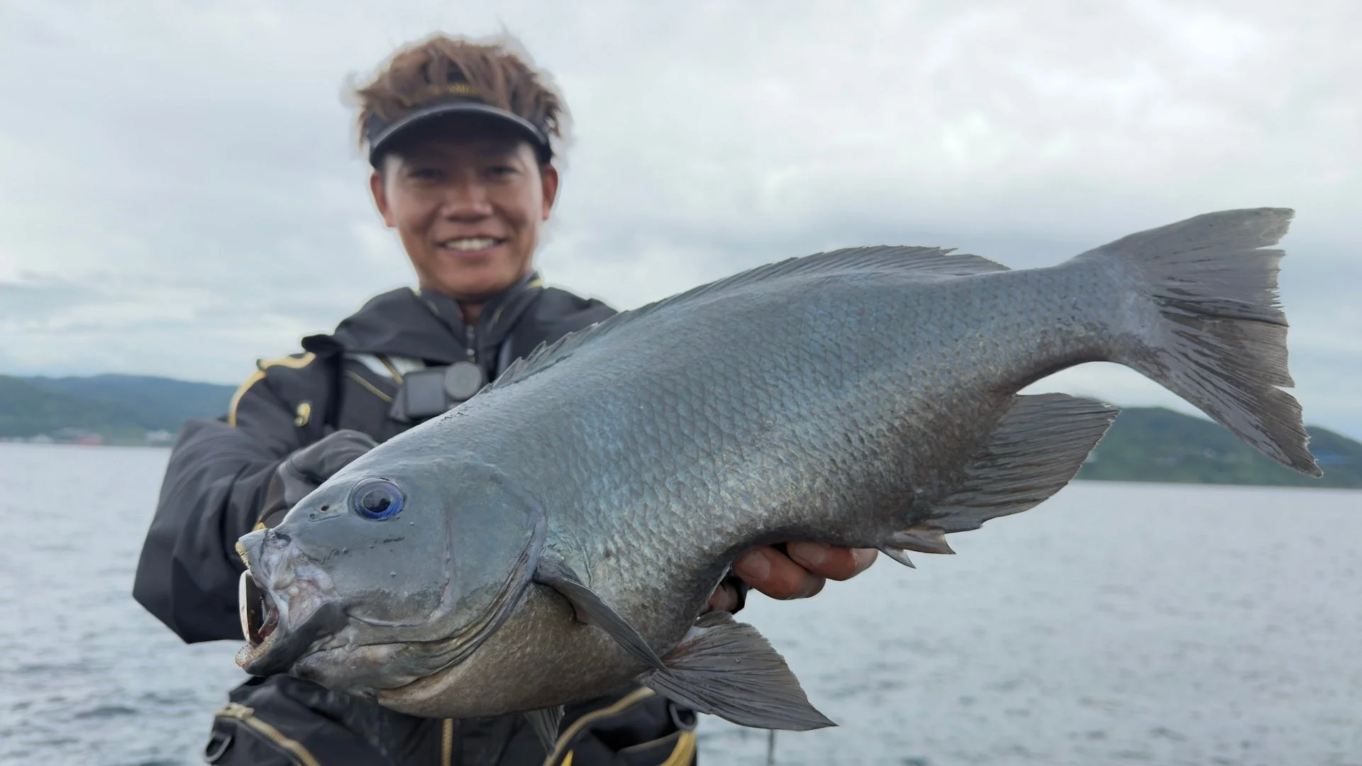 釣り上げた魚を笑顔で掲げる池田翔悟氏
